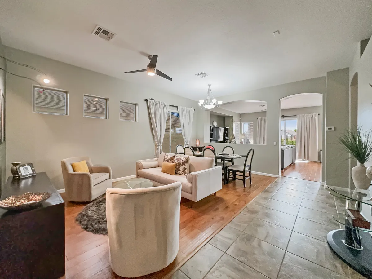 A comfortable living and dining area with a sofa adorned with decorative pillows, a dining table with chairs, and large windows letting in abundant natural light. The space feels cozy and welcoming, ready for family gatherings, reading, or relaxed socializing.