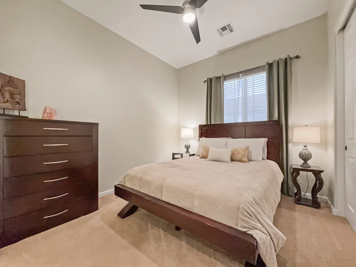 A tranquil bedroom scene showcasing a neatly made bed, a stylish nightstand, a dresser, and a window letting in gentle daylight. The space feels calm and welcoming, perfect for guests or teens seeking comfort and privacy.
