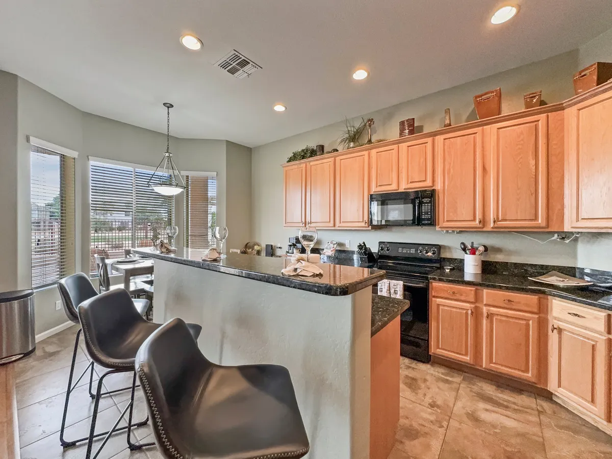 A modern kitchen with a central island, bar stools, ample cabinetry, and kitchen appliances. Multiple windows let light stream in, and the open design invites both casual breakfasts and lively meal preparations.