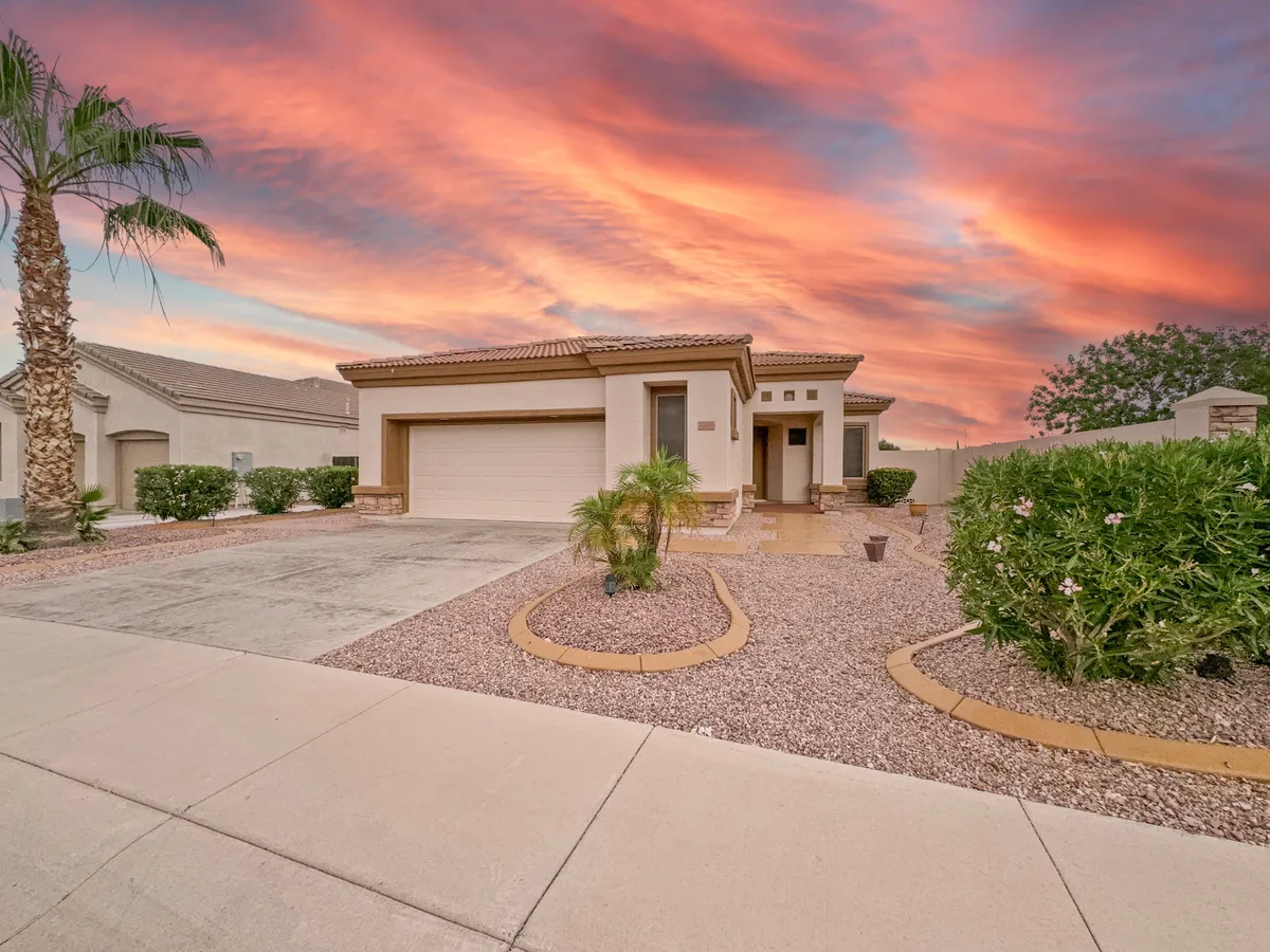 An exterior scene with striking modern architecture, a vibrant sunset sky, and a landscaped garden. The inviting outdoor space sets the stage for gatherings or relaxation and suggests a welcoming neighborhood environment.