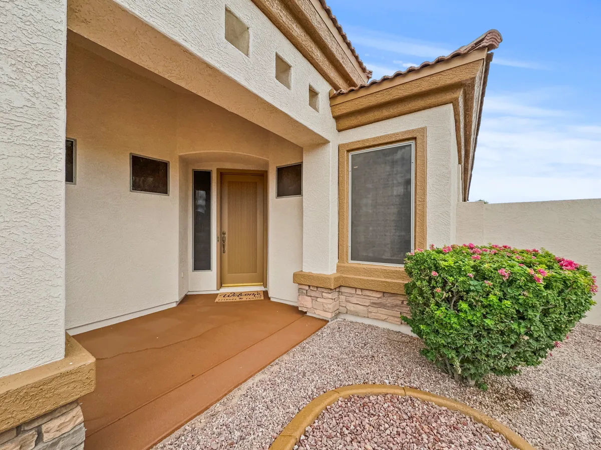 A welcoming front door and landscaped entryway set the scene for a friendly and inviting home. The textured walls, greenery, and cozy porch area hint at neighborly connections and the private-yet-connected feel of Seville homes.